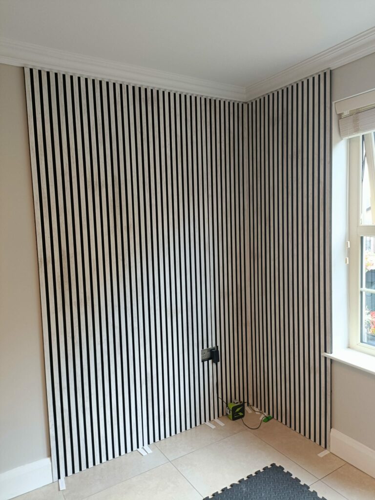 Room corner with vertical black and white striped wall, tile flooring, and a window on the right.