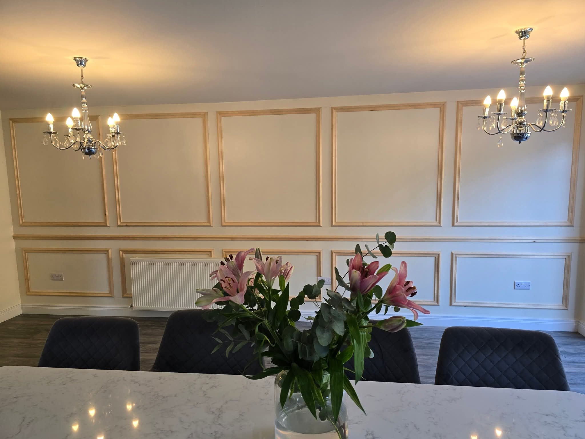 Elegant dining room with ornate French panelling, floral centerpiece, and chandeliers.