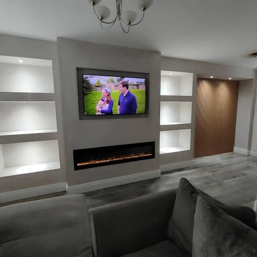 Modern living room with media wall, recessed lighting, mounted TV, and electric fireplace.