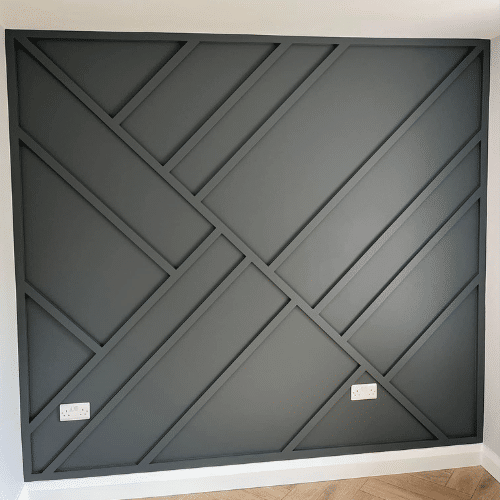 Geometric dark gray accent wall with diagonal paneling in a modern interior room.