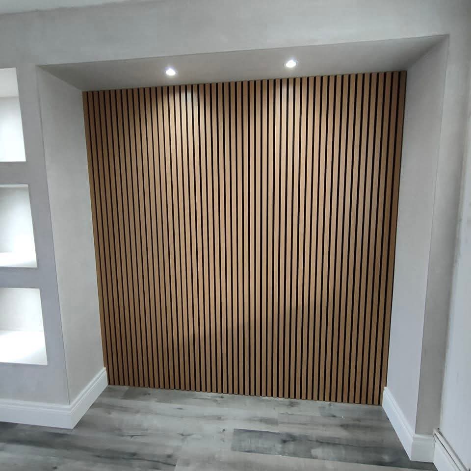 Modern acoustic slat wall with wooden panels, flanked by alcove shelves and overhead lighting.