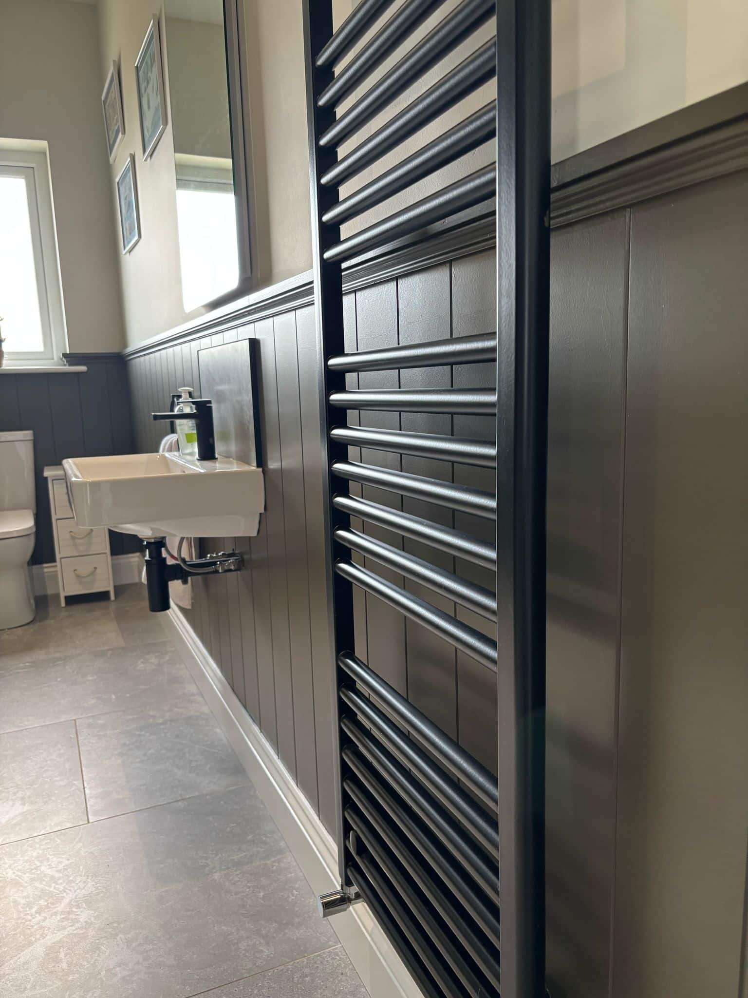 Bathroom with modern radiator, white sink, and wall mirror.