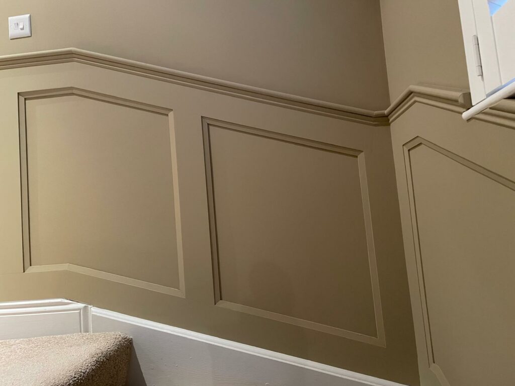 Staircase with beige wall paneling and white trim accents.