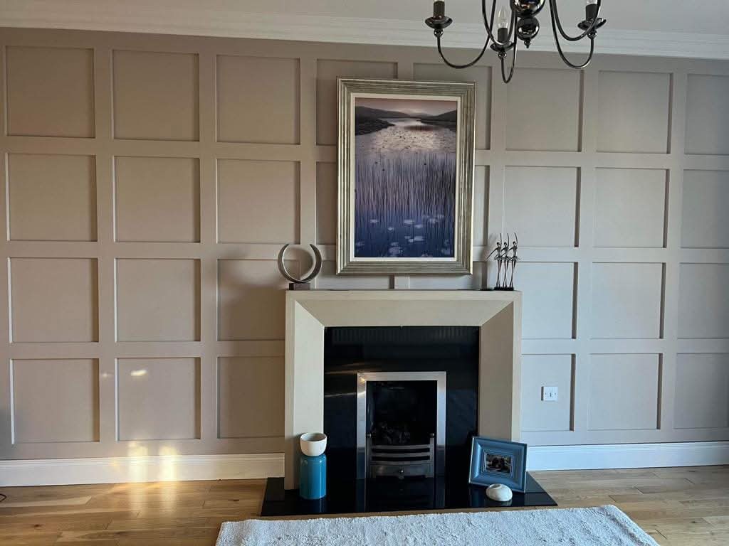 Elegant living room with framed landscape art above a modern fireplace and decorative items on the mantel.