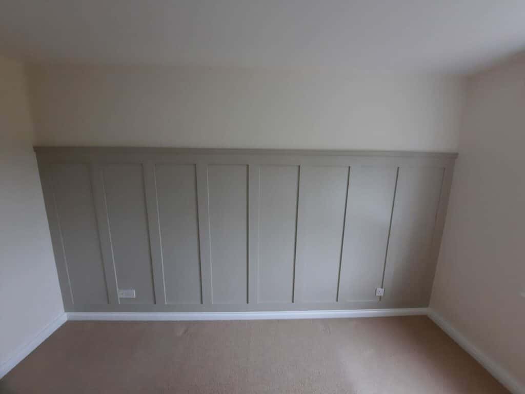 Empty room with beige wall paneling and light brown carpet.