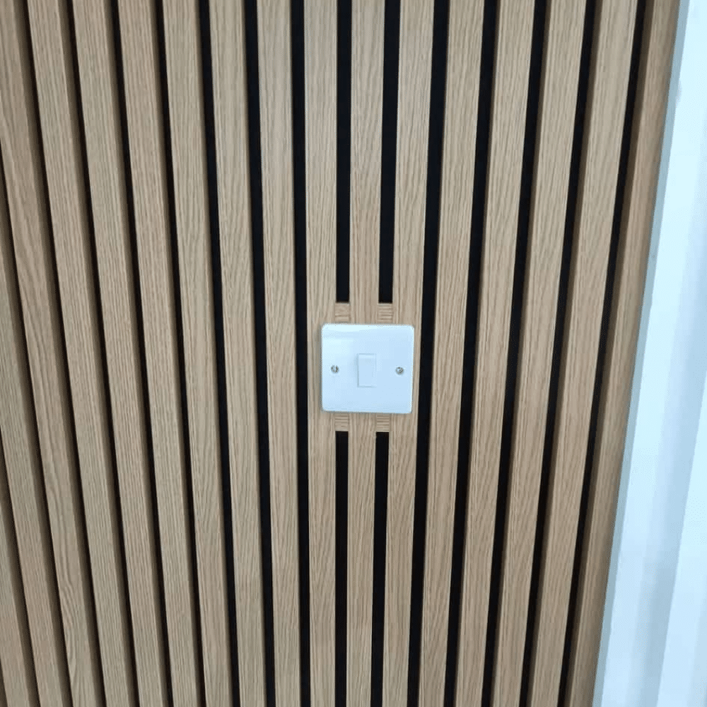 Light switch on a wall with vertical wooden slats design.