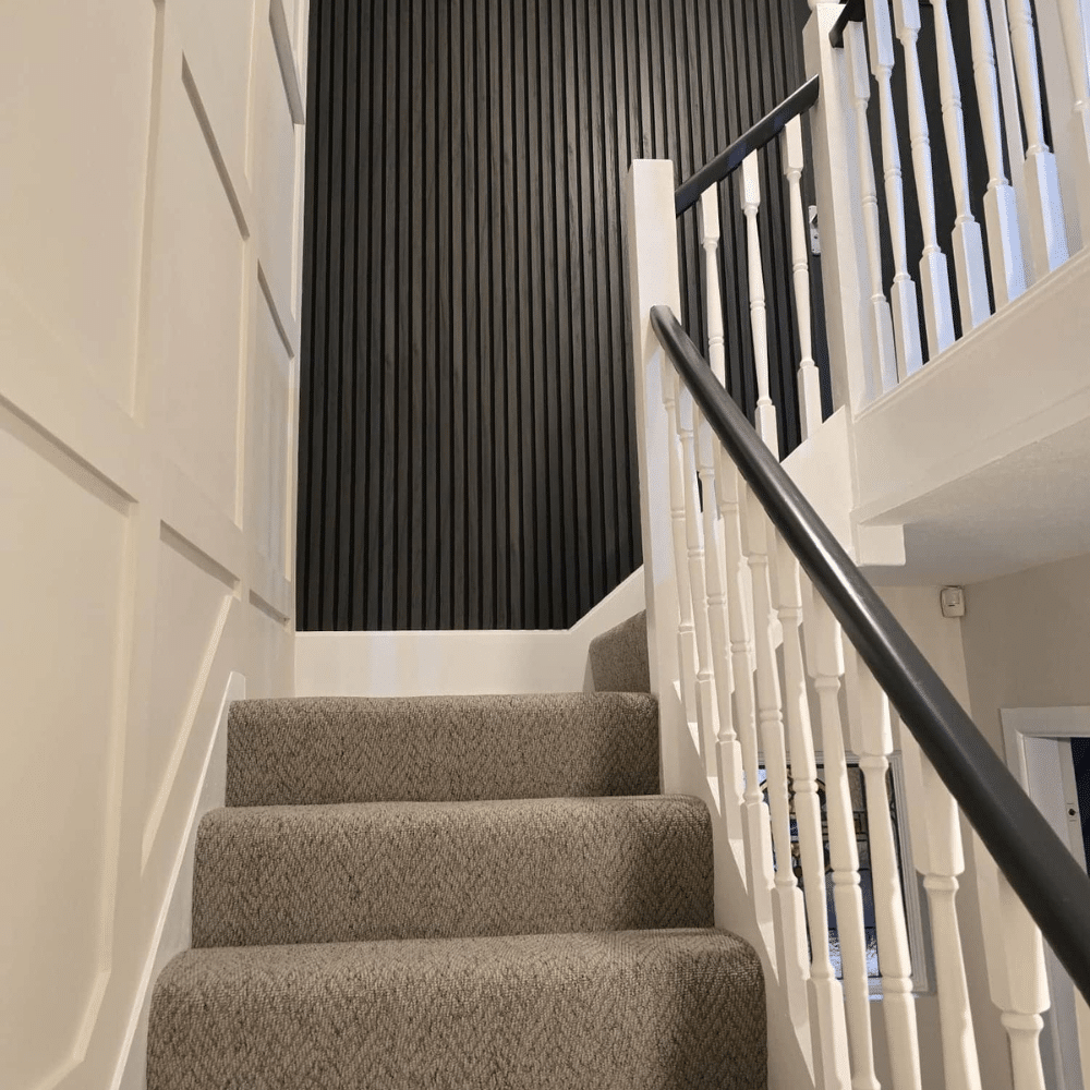 Carpeted staircase with white railings and a black textured accent wall.