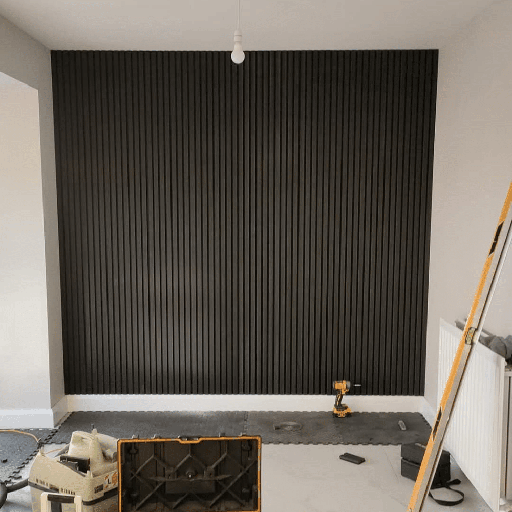 Black slatted accent wall with tools and a ladder in a room under renovation.