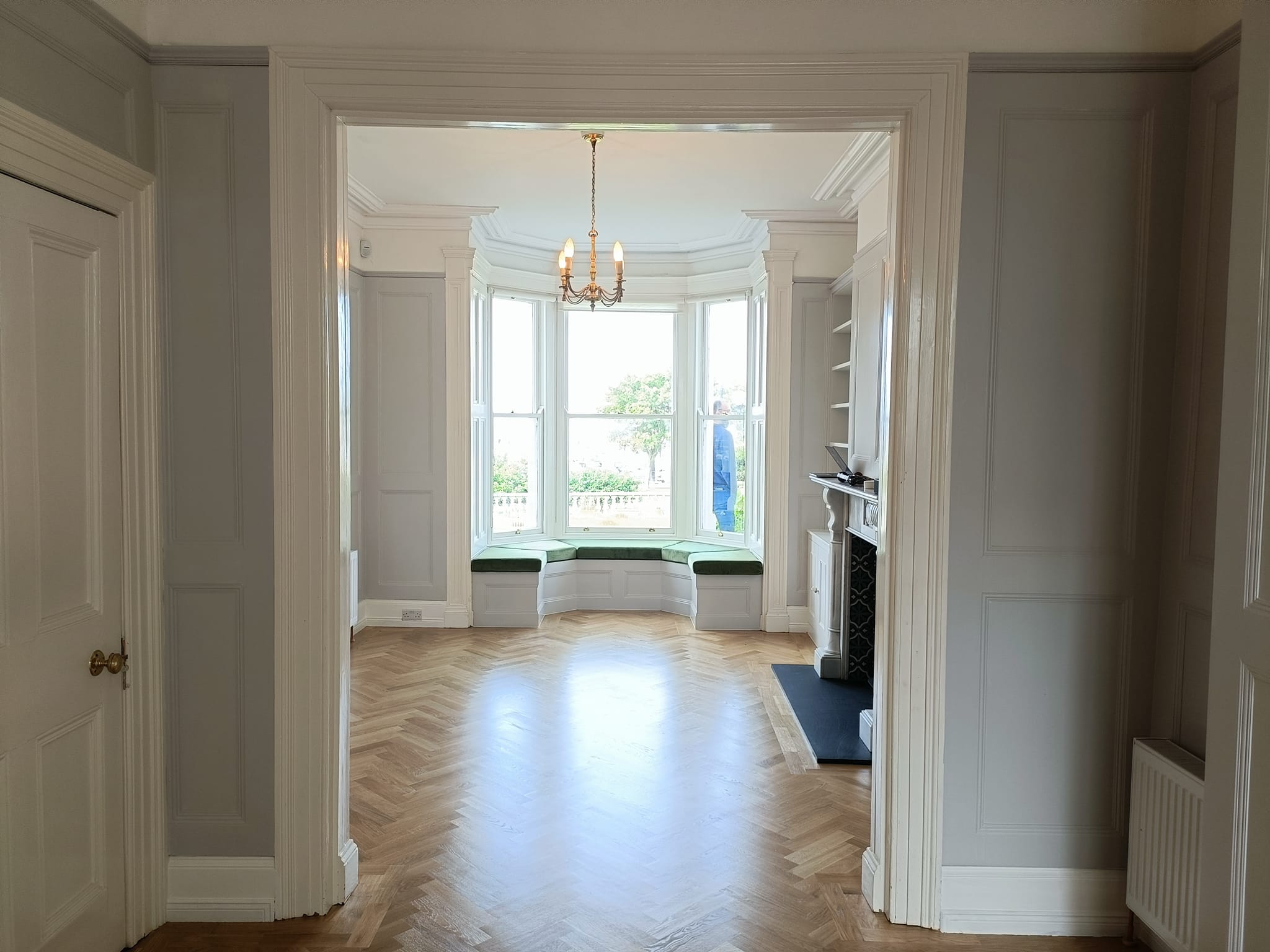 Stylish living room with large bay windows, parquet floors, and elegant molding.