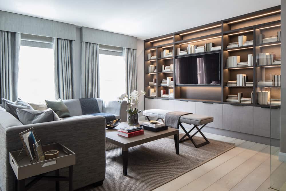 Modern living room with bespoke joinery, large bookcase, sofa, and neutral decor by Roselind Wilson Design.